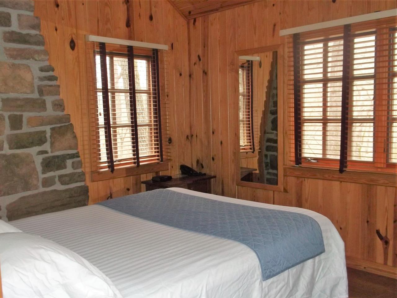 A view of one of the bedrooms in cabin 10 including a bed, mirror and two exterior windows